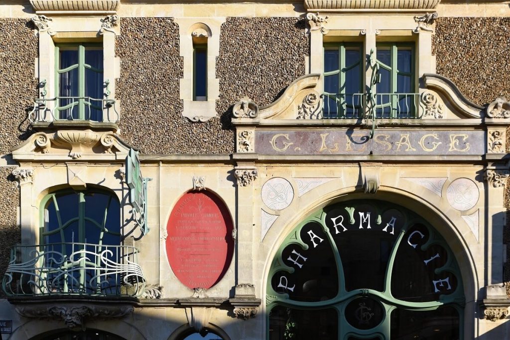 Part of the art-deco façade of the pharmacy in Douvres-la-Délivrande. The photo shows the top of the entrance door and the second floor. 