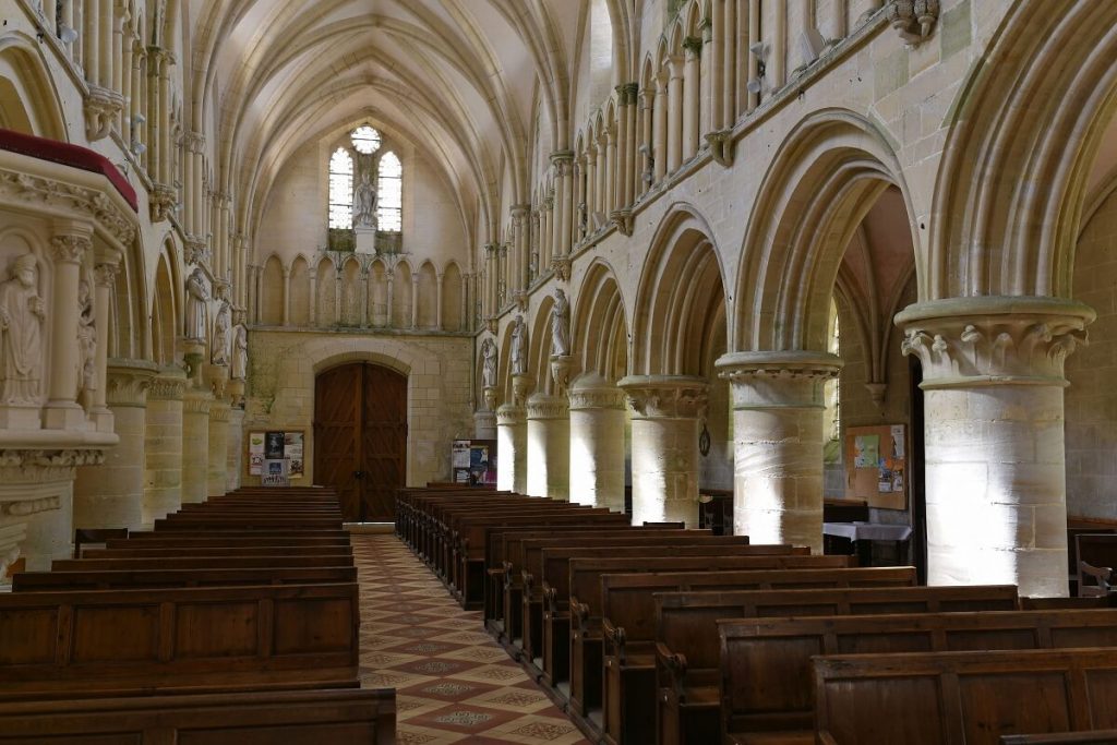 Nef de l'église de Langrune prise depuis le cœur. La voute est faite d'arcs brisées et les ouvertures sur les côtés latéraux de la nef en arc plein ceintre supporté par des piliers massifs.