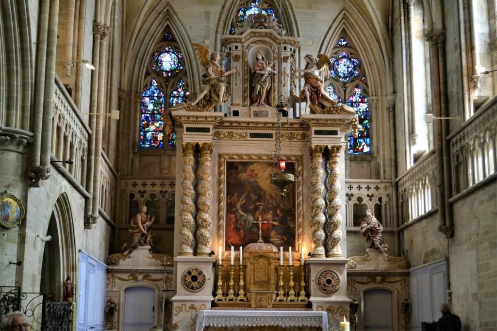 The altarpiece in the church at Bernières is part of a monumental ensemble in the white and gold Baroque style, with double twisted columns, surmounted by statues of the three archangels.