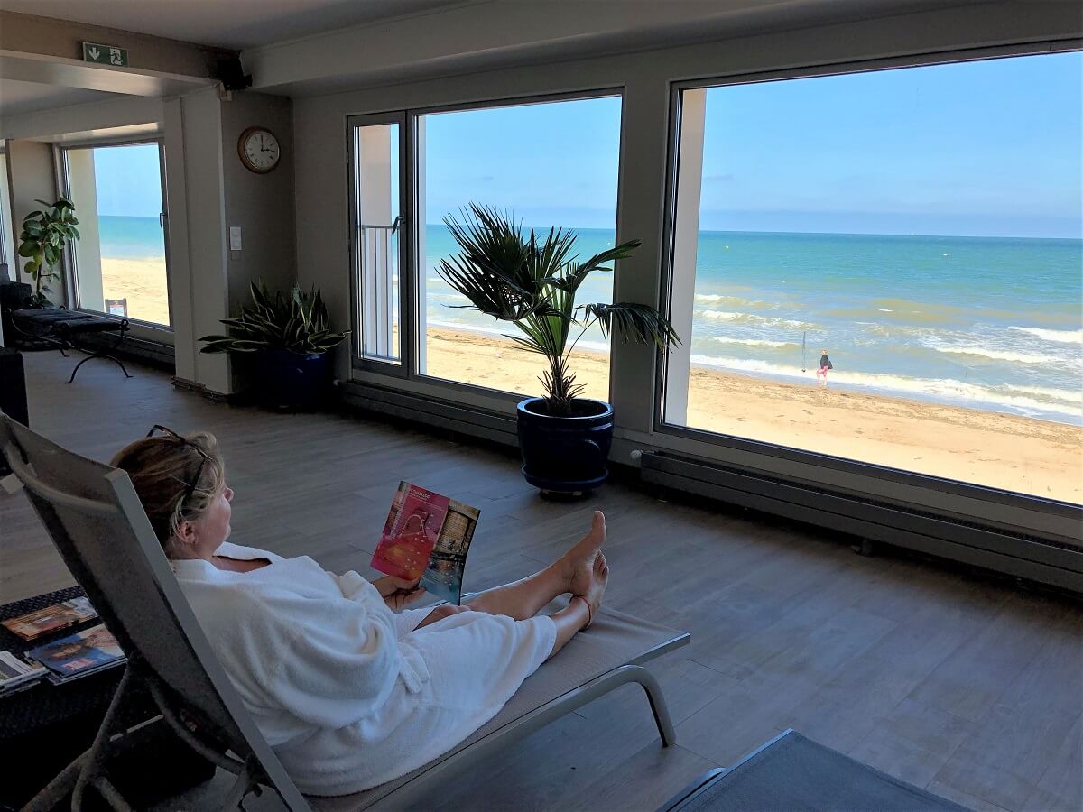 Liggend op een ligstoel geniet een vrouw van de ontspanningsruimte in het 3 mondes thalasso in Luc-sur-mer, waar de grote ramen uitkijken over het strand. - krediet: Mathilde Lelandais