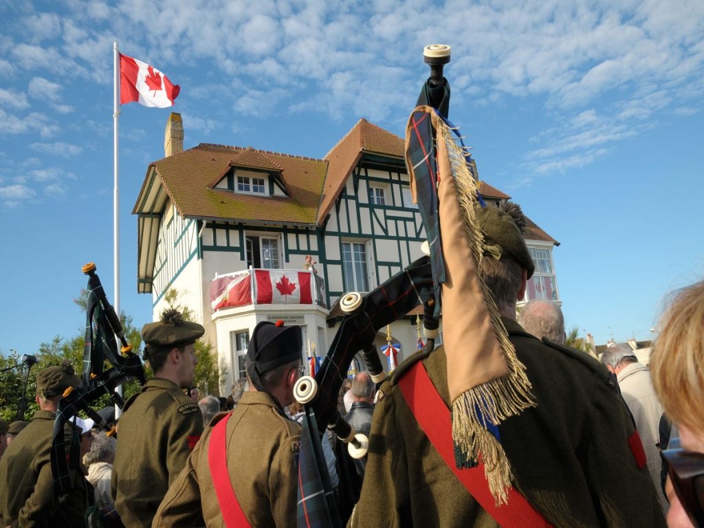 D-Day ceremony in front of the Canadians' house in Bernières, with two bagpipers in uniform in the background. - credit: Francois Dupont