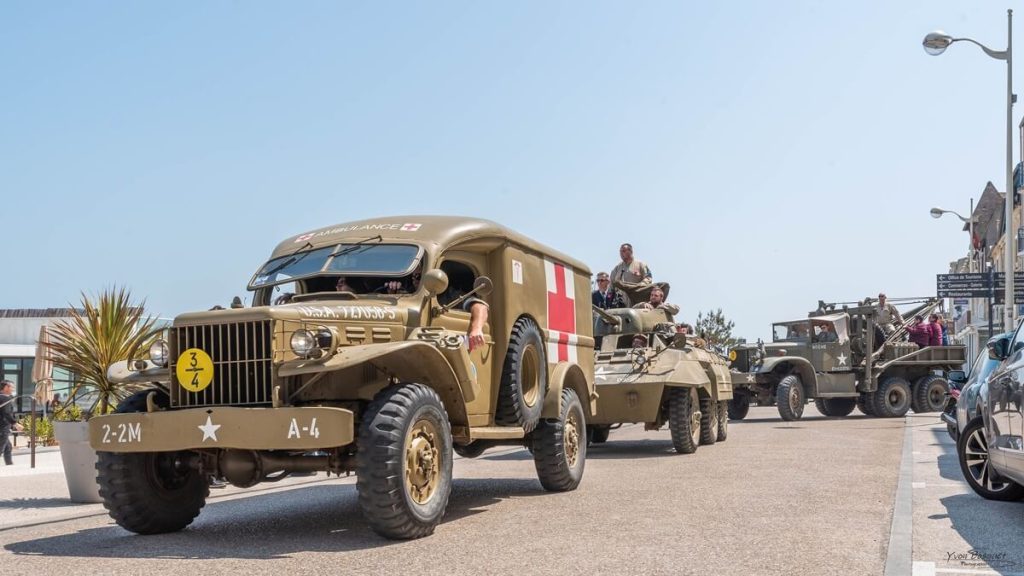 grand parade featuring civilian and military vehicles from World War II