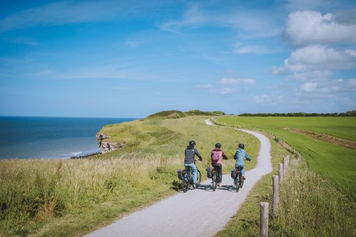 Trois cyclistes sur la voie verte de la Liberté (Vélomaritime) longeant les falaises et la mer.